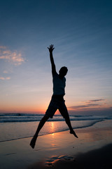 Man jumping on the beach at the sunset
