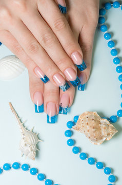 Fingernails with blue french manicure on decorated background