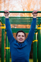 Obraz premium Athletic man doing pull-up on horizontal bar
