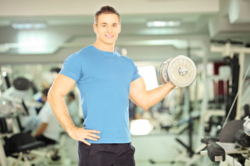 Smiling muscular man lifting weight in fitness club