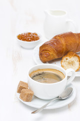 cup of black coffee and croissants with orange jam