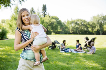 Happy Mother Carrying Daughter At Park