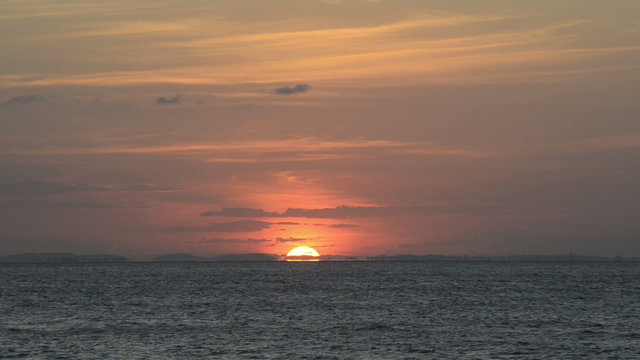 Sun setting as a ball of fire on the horizon over the ocean