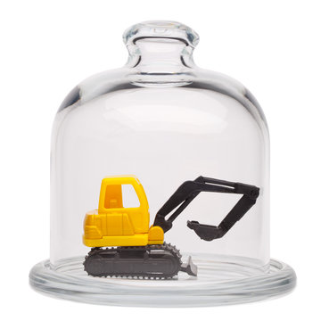 Toy yellow excavator in a glass dome