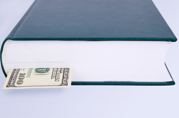 closed green book with a bookmark 100 USD