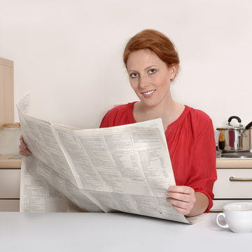 Hübsche rothaarige Frau liest Zeitung