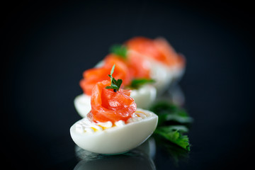 boiled egg with salty salmon on black background