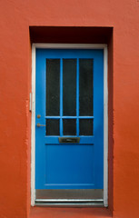 Fototapeta na wymiar Blue wooden door on a red wall, Reykjavik, Iceland