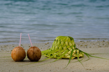 Two coconuts and sun hat on the sandy sea shore