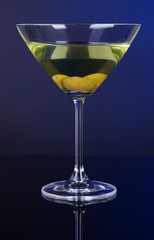 Martini glass with olives on dark blue background