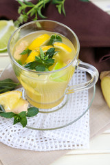Cup of tea with ginger on napkin on wooden table