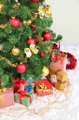 Decorated Christmas tree with gifts on grey wall background