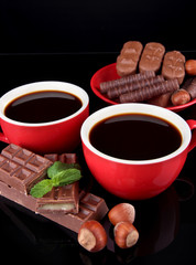 Red cups of strong coffee and chocolate bars close up