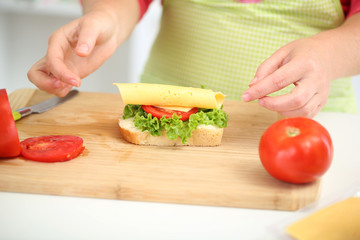 Happy smiling woman in kitchen preparing  sandwich, close up