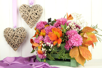 Flowers composition in crate with decorative hearts