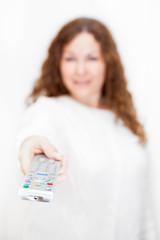 Tv remote control on foreground in hand with defocused woman
