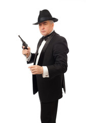 The elegant man in a tuxedo with a hat and a revolver 