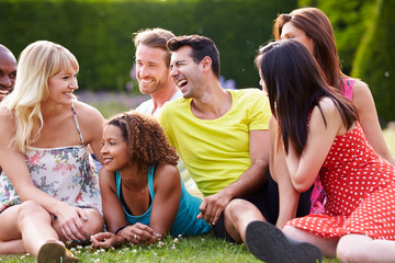 Group Of Friends Sitting On Grass Together