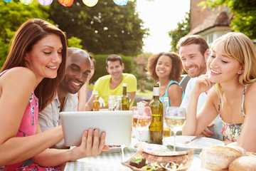 Friends Having Barbeque At Home Looking At Digital Tablet