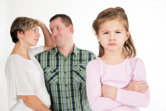 Beleidigtes Kind, genervte Eltern im Hintergrund