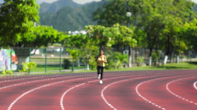 A young woman running at a track in a stadium