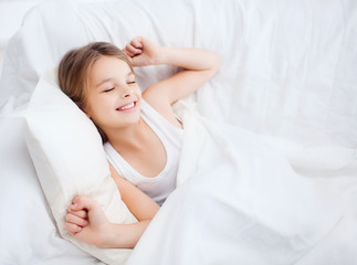 Fototapeta na wymiar smiling girl child waking up in bed at home