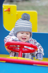 Fototapeta na wymiar smiling baby driving car on playground