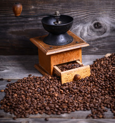 Manual coffee grinder with beans on wooden background