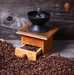 Manual coffee grinder with beans on wooden background