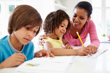 Mother Helping Children With Homework In Kitchen