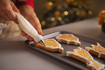 Closeup on young housewife decorating christmas cookies with gla - obrazy, fototapety, plakaty