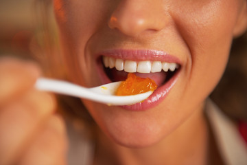 Closeup on happy young woman eating orange jam - obrazy, fototapety, plakaty