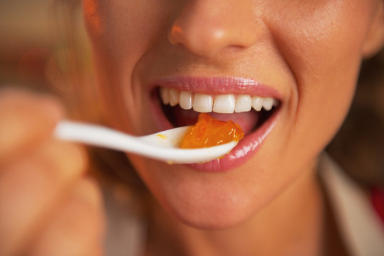 Naklejki Closeup on happy young woman eating orange jam
