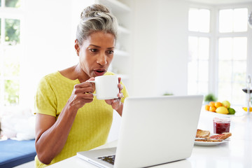 African American Woman Using Laptop In Kitchen At Home