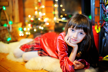 Child girl by a fireplace on Christmas