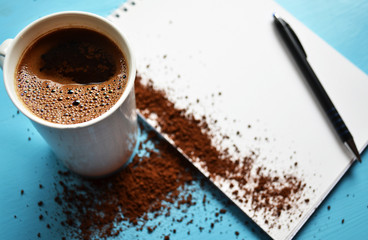 Cup of black coffee on blue background and blank paper