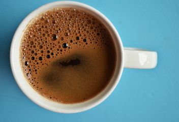 Cup of black coffee on blue background