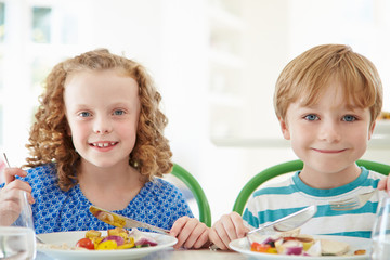 Fototapeta premium Two Children Eating Meal At Home Together