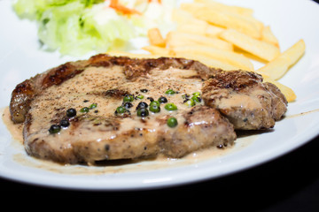 Beef steak with black pepper sauce on a white plate