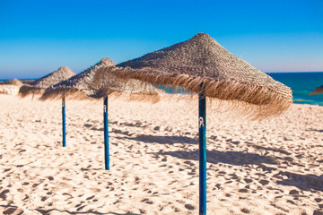 Straw umbrellas on empty tropical beach on the Atlantic coast