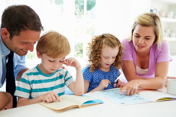 Parents Helping Children With Homework In Kitchen