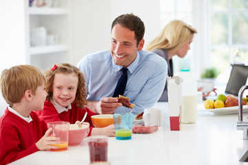 Family Having Breakfast In Kitchen Before School And Work