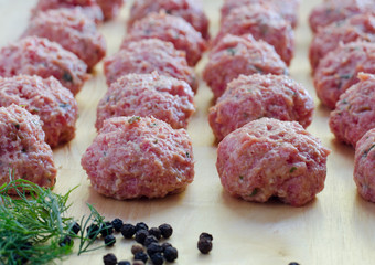 raw seasoned meatballs on a cutting board