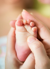 mother hands holding infant baby foot