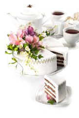 white cake decorated with sugar flowers and a cup of tea