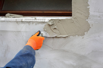 Worker spreading  mortar over styrofoam insulation with trowel