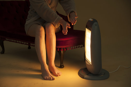 Woman keeping warm by an electric fire