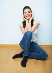 Woman natural portrait. Smiling girl seat on a floor. White bac