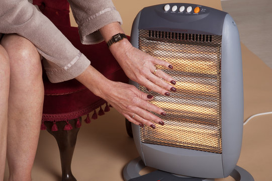 Woman Keeping Warm By An Electric Fire