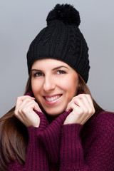 young woman wearing cap and smiling on light background